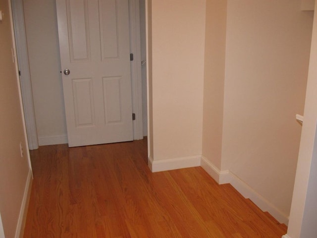 corridor with light wood finished floors and baseboards