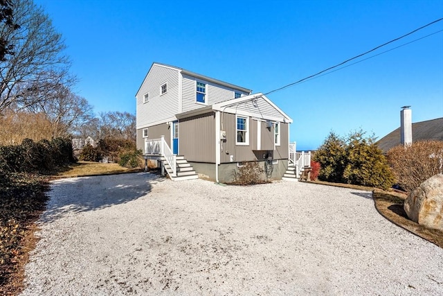 rear view of property featuring gravel driveway