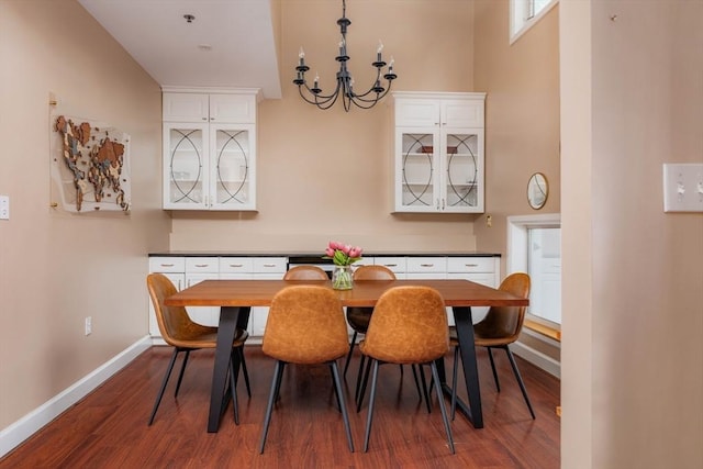 dining area with dark wood-style floors, a notable chandelier, and baseboards