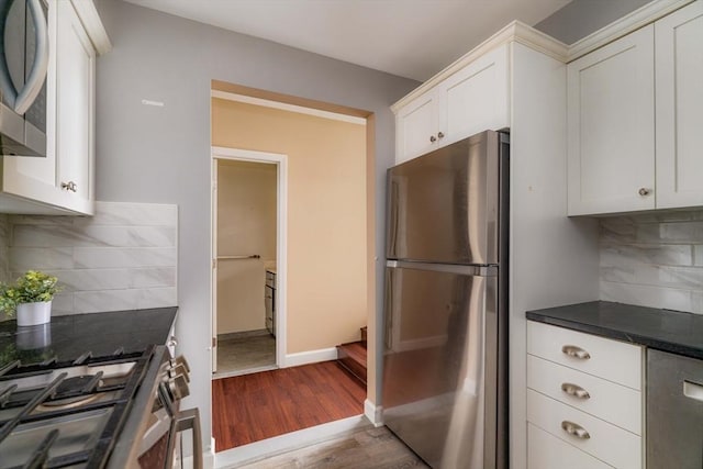 kitchen featuring white cabinetry, baseboards, appliances with stainless steel finishes, backsplash, and dark wood finished floors