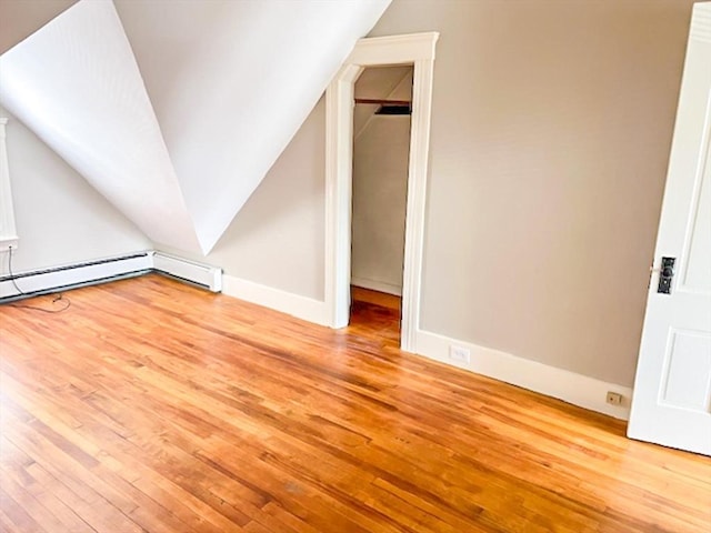 additional living space with wood-type flooring, lofted ceiling, and baseboards
