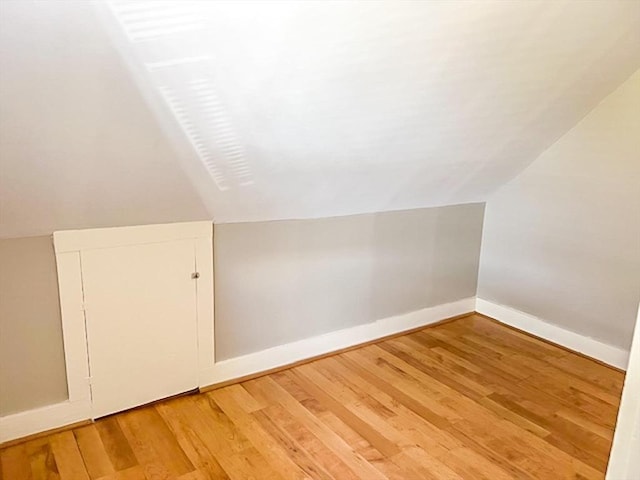 bonus room featuring vaulted ceiling, light wood-type flooring, and baseboards