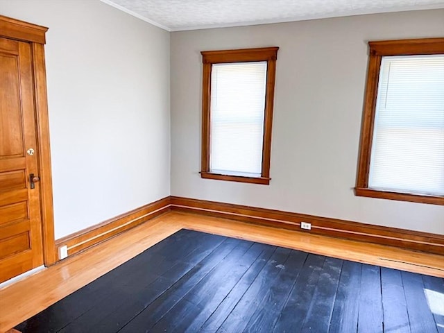 unfurnished room featuring hardwood / wood-style floors, baseboards, healthy amount of natural light, and ornamental molding