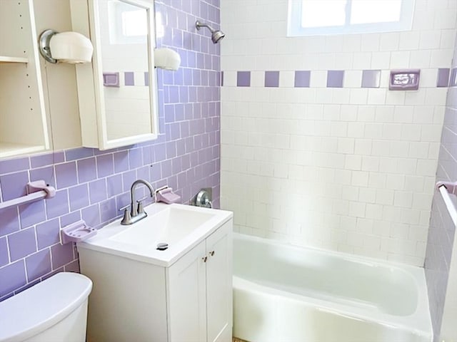 bathroom featuring toilet, tile walls, plenty of natural light, vanity, and bathing tub / shower combination