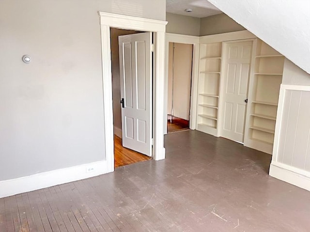 bonus room featuring baseboards, built in features, and wood finished floors