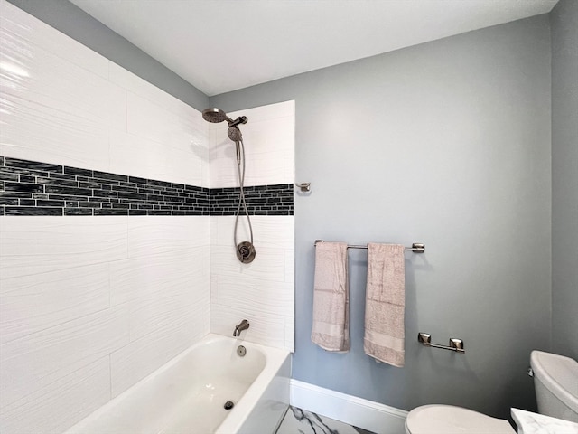 bathroom featuring tiled shower / bath combo and toilet