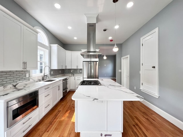 kitchen featuring pendant lighting, island range hood, appliances with stainless steel finishes, a kitchen island, and white cabinetry