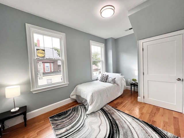 bedroom with multiple windows and hardwood / wood-style flooring