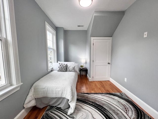 bedroom with hardwood / wood-style flooring and lofted ceiling