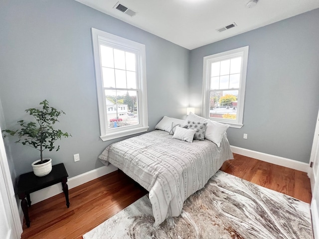 bedroom with multiple windows and hardwood / wood-style floors