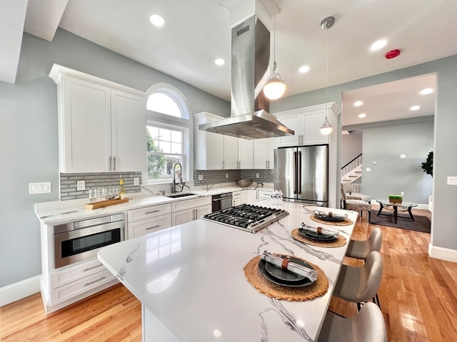 kitchen with tasteful backsplash, stainless steel appliances, island range hood, light hardwood / wood-style flooring, and white cabinetry