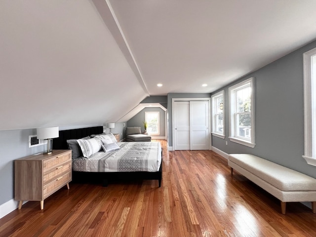 bedroom with a closet, lofted ceiling, dark wood-type flooring, and multiple windows