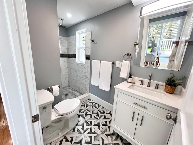 bathroom featuring toilet, vanity, and tiled shower