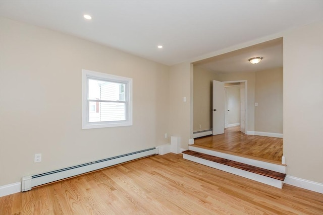 empty room featuring a baseboard heating unit, light wood finished floors, baseboards, and recessed lighting