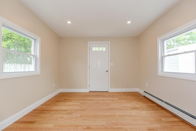 unfurnished room featuring a baseboard heating unit, healthy amount of natural light, light wood-type flooring, recessed lighting, and baseboards
