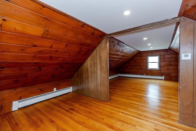 additional living space featuring a baseboard radiator, wood finished floors, lofted ceiling, and wood walls