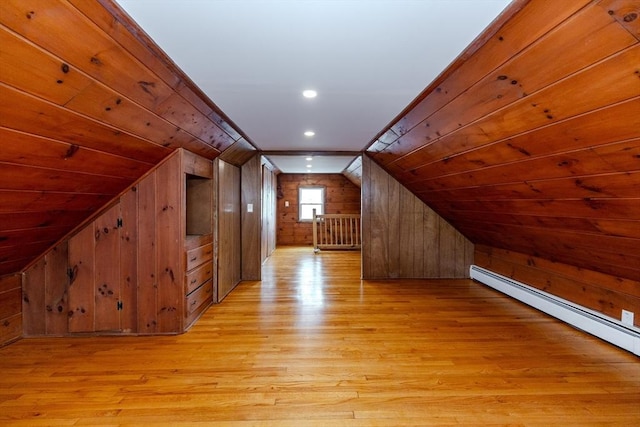 additional living space with wood walls, lofted ceiling, light wood finished floors, and a baseboard heating unit