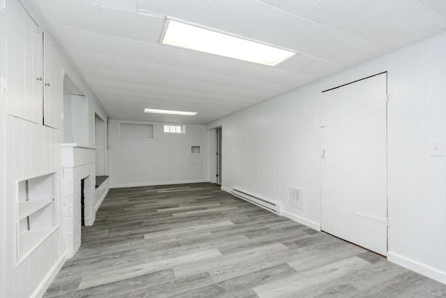 below grade area with baseboard heating, wood finished floors, and baseboards