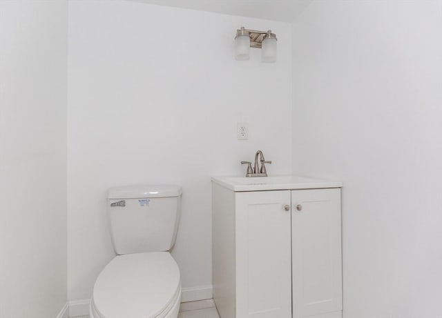 bathroom featuring toilet, baseboards, and vanity