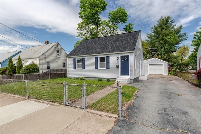view of front facade with a garage, asphalt driveway, roof with shingles, an outbuilding, and a gate