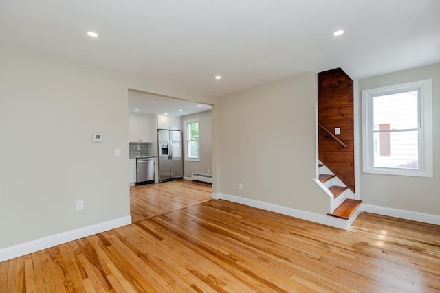 unfurnished living room featuring stairway, light wood-style floors, recessed lighting, baseboards, and a baseboard heating unit