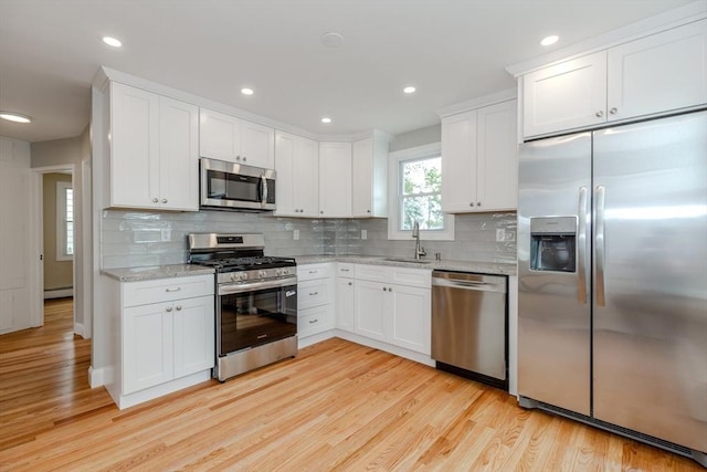 kitchen featuring appliances with stainless steel finishes, light wood-type flooring, white cabinetry, decorative backsplash, and recessed lighting