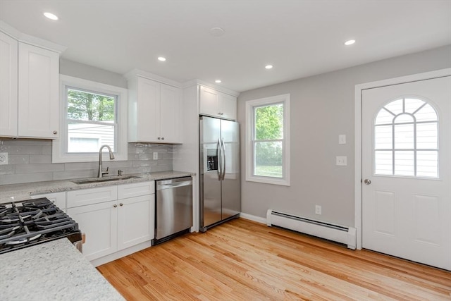 kitchen featuring stainless steel appliances, baseboard heating, a sink, plenty of natural light, and recessed lighting