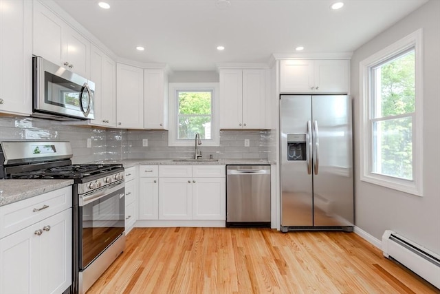 kitchen with appliances with stainless steel finishes, baseboard heating, a sink, healthy amount of natural light, and recessed lighting