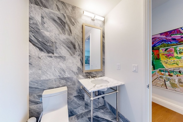 bathroom featuring tile walls, toilet, sink, and hardwood / wood-style floors