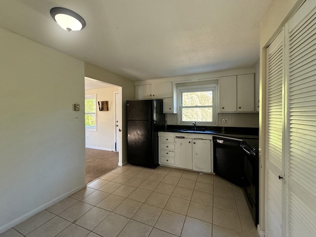 kitchen featuring sink, white cabinets, black appliances, and light tile patterned floors