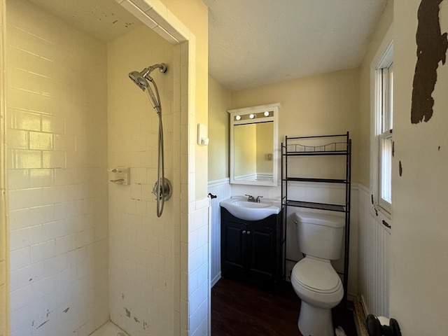 bathroom with hardwood / wood-style floors, vanity, toilet, and a tile shower