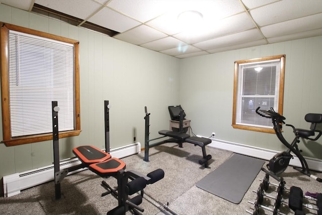 workout room with a baseboard heating unit, a paneled ceiling, and carpet flooring