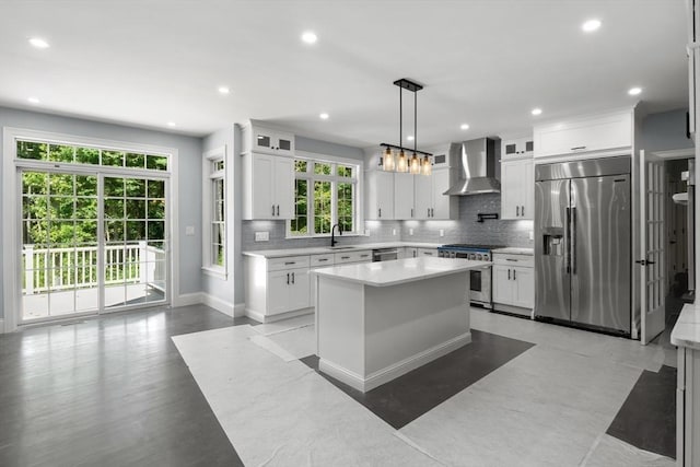 kitchen featuring pendant lighting, a center island, high end appliances, wall chimney exhaust hood, and white cabinetry