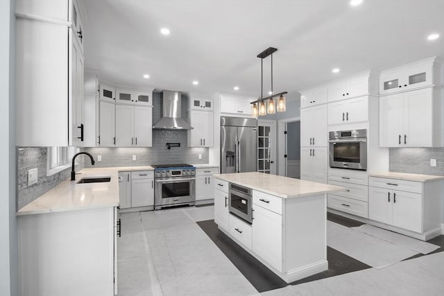 kitchen with built in appliances, wall chimney exhaust hood, a center island, and white cabinets