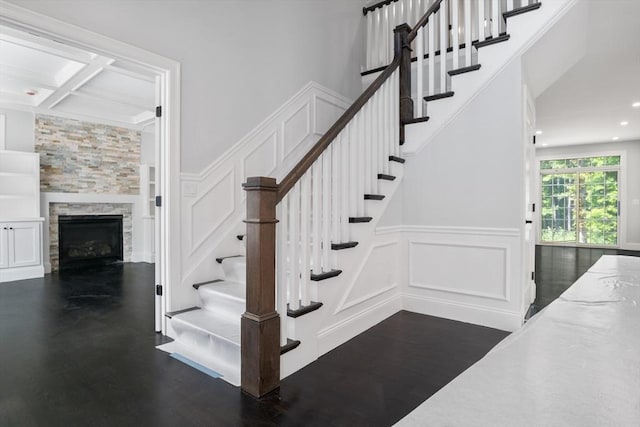 stairway featuring hardwood / wood-style flooring, a fireplace, and coffered ceiling