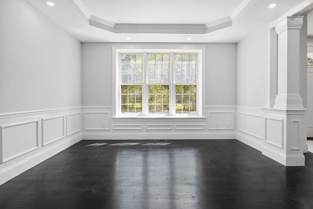 unfurnished room featuring a raised ceiling, ornate columns, and dark hardwood / wood-style flooring