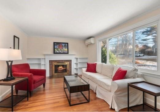 living room with a fireplace, a wall unit AC, and wood-type flooring