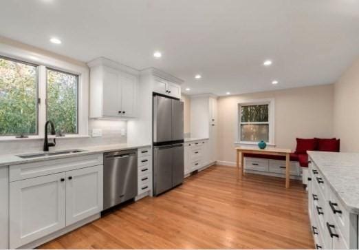 kitchen featuring sink, white cabinetry, light wood-type flooring, and appliances with stainless steel finishes