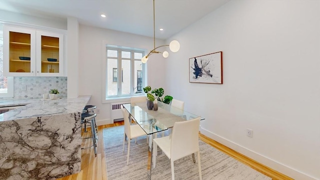 dining area featuring recessed lighting, baseboards, radiator, and light wood finished floors