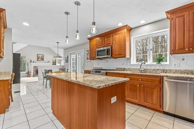 kitchen featuring a sink, stainless steel appliances, light stone counters, and a kitchen island