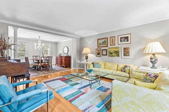 living area featuring baseboards, crown molding, an inviting chandelier, and wood finished floors