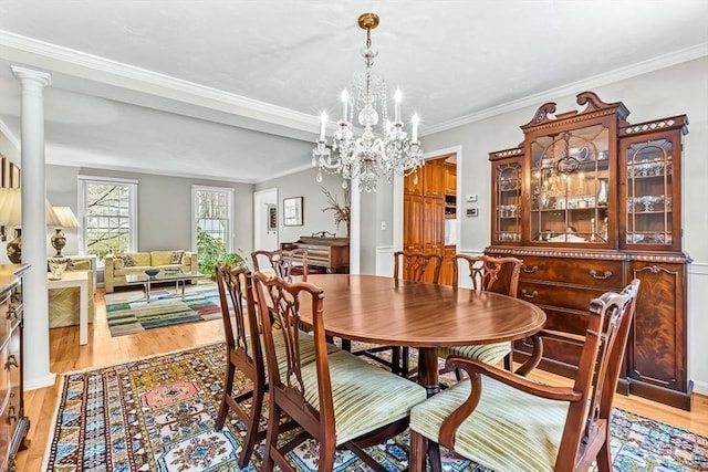 dining space with light wood-type flooring, an inviting chandelier, and ornamental molding