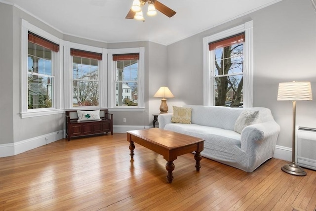 living room featuring ceiling fan, crown molding, baseboards, and hardwood / wood-style flooring