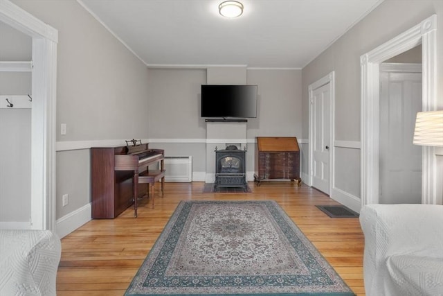 living area with ornamental molding, a wood stove, and wood finished floors