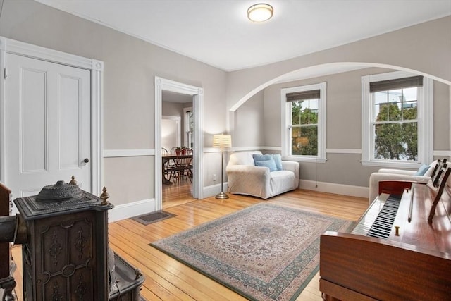 sitting room with arched walkways, visible vents, baseboards, and hardwood / wood-style floors