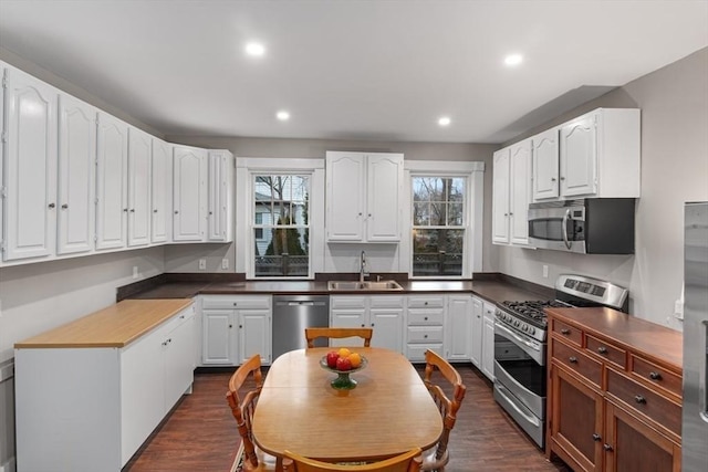 kitchen with a sink, dark wood-style flooring, white cabinetry, and stainless steel appliances