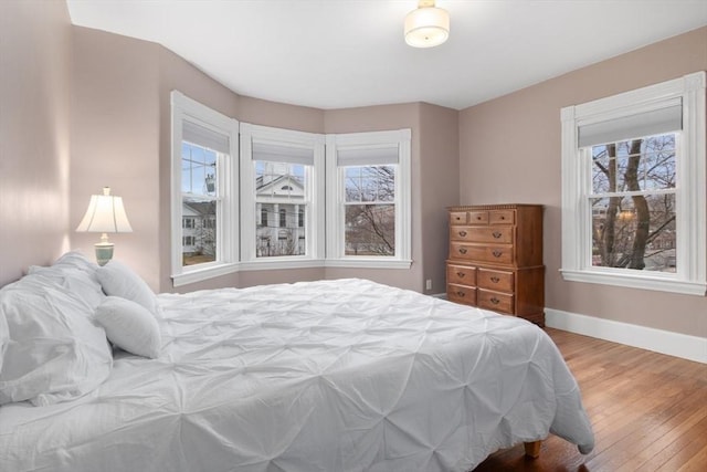 bedroom with baseboards, multiple windows, and hardwood / wood-style flooring