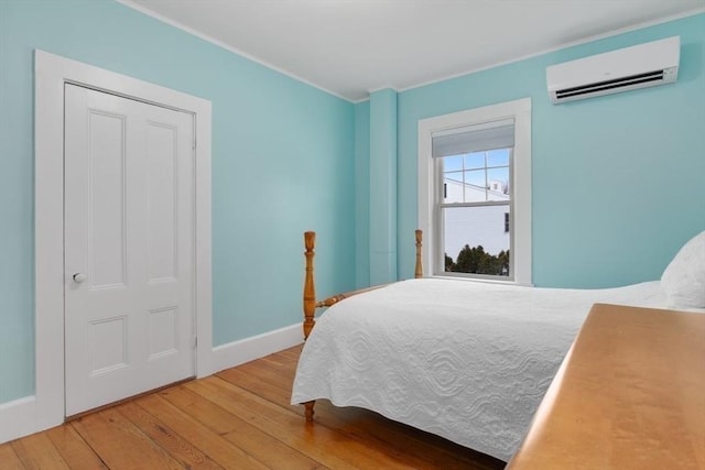 bedroom with ornamental molding, an AC wall unit, baseboards, and hardwood / wood-style floors