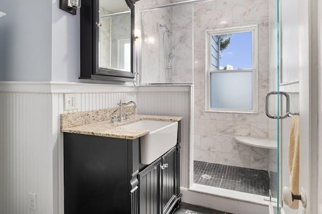 full bath with a wainscoted wall, a stall shower, and vanity