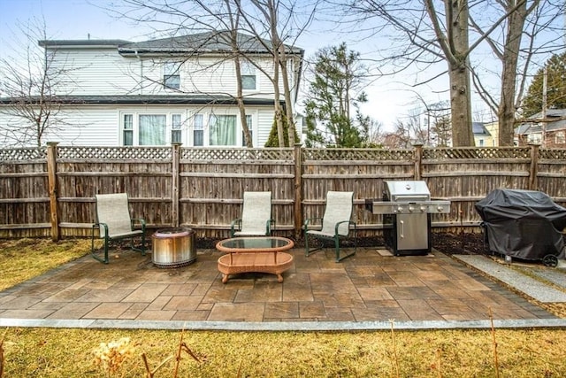 view of patio / terrace featuring area for grilling, fence, and a fire pit